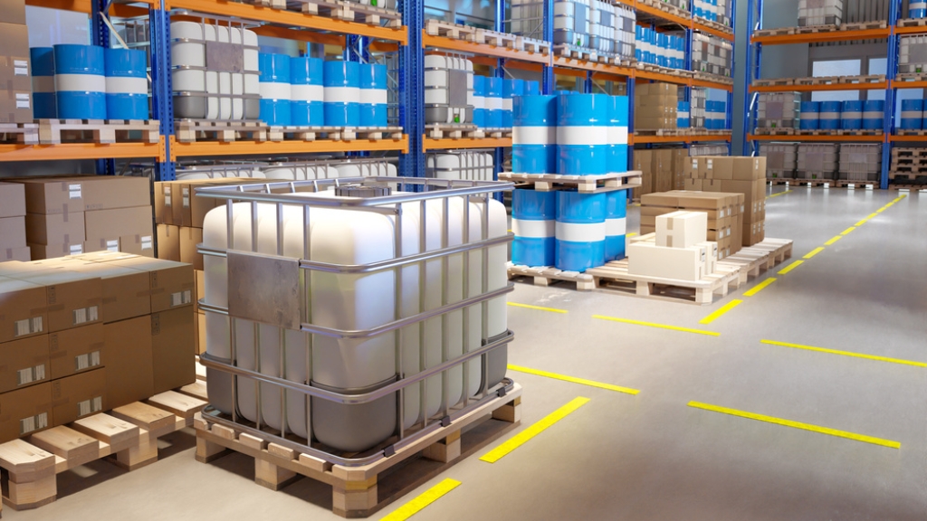 Warehouse stock of ZDDP lubricant additive, stacked 200L blue metal drums and 1000L IBC plastic tote tanks for bulk export