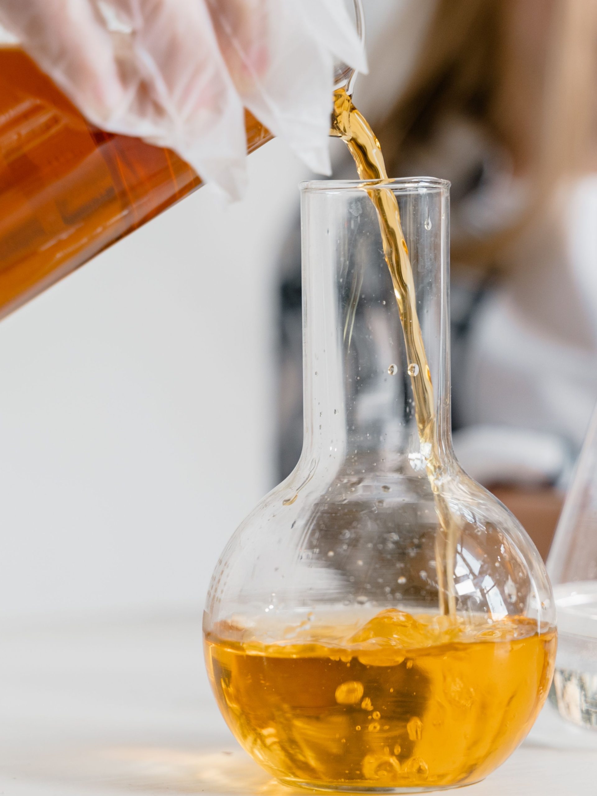 Sulfurized Isobutylene T321 amber lubricant additive liquid pouring into lab flask