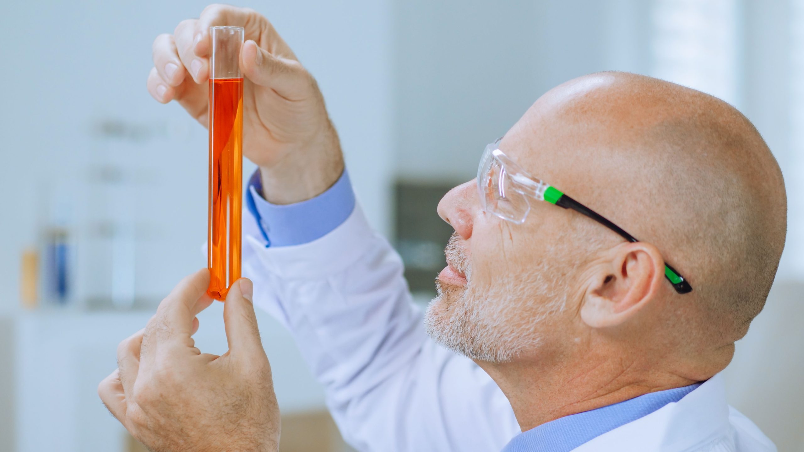 Technician inspecting metal working fluid additives sample in test tube for quality control