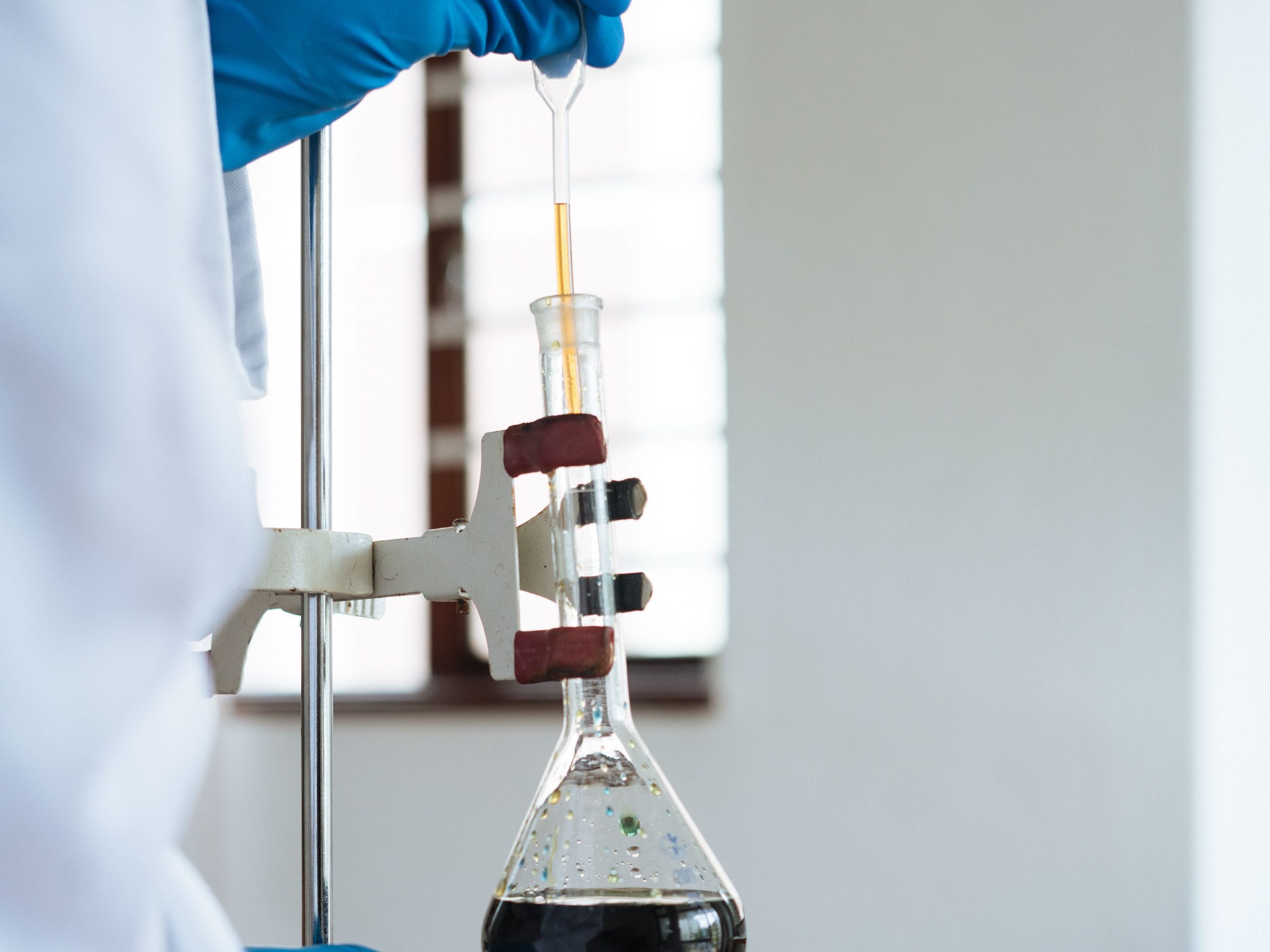Laboratory technician testing lubricant additive components using precision dropper in Shanghai Rad Chemical lab