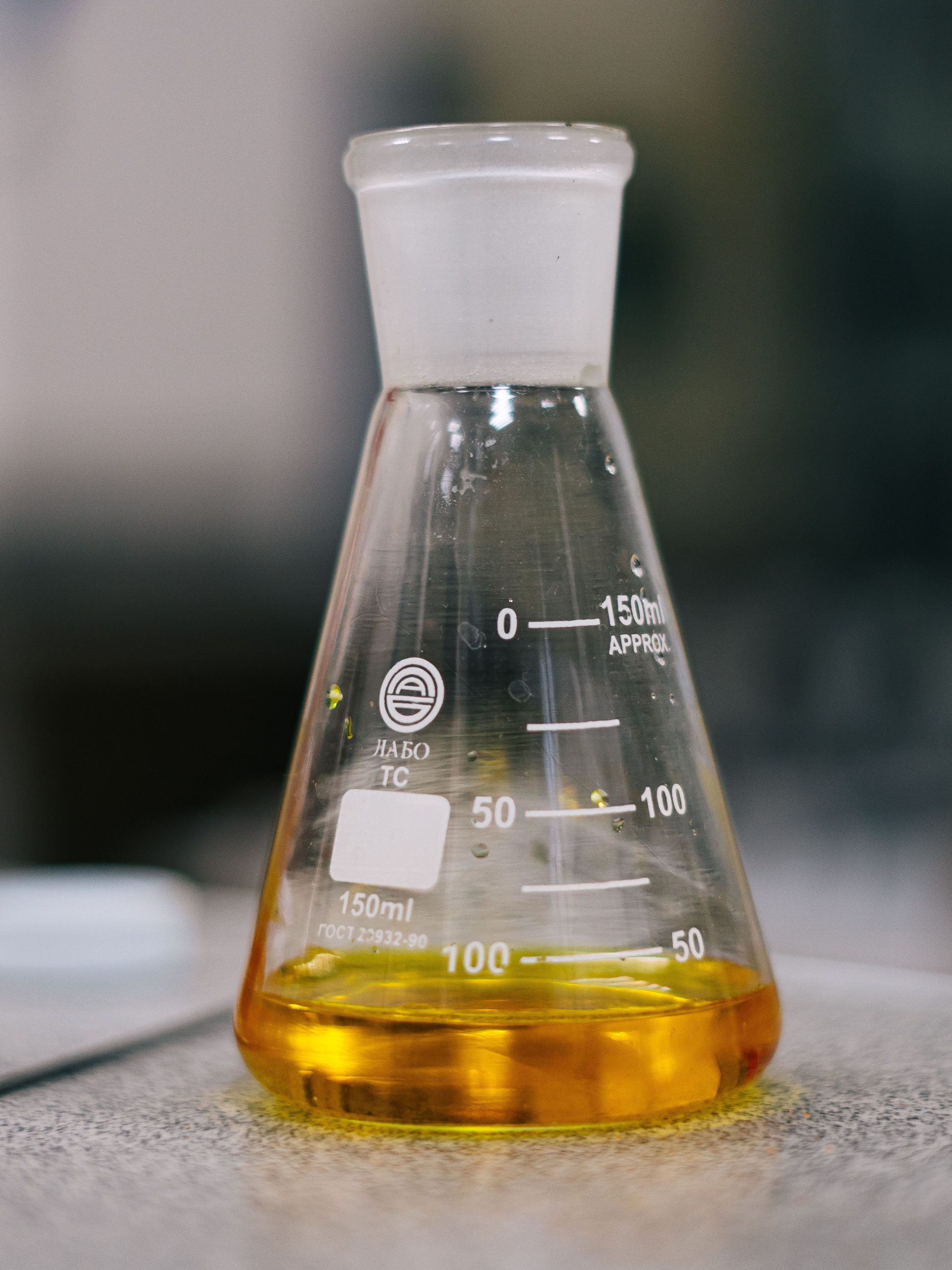 Sulfurized Fatty Acid Ester golden‑orange lubricant additive liquid in Erlenmeyer flask lab sample